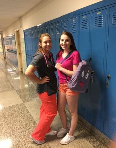 Two young women standing by some lockers in a hallway
