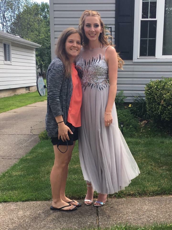 Two people, one wearing the same dress the author was wearing in the first picture, standing outside a house