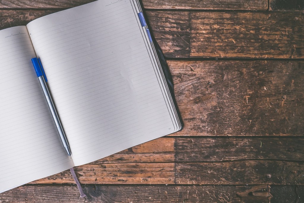 Picture of a journal and a pen on a wooden table